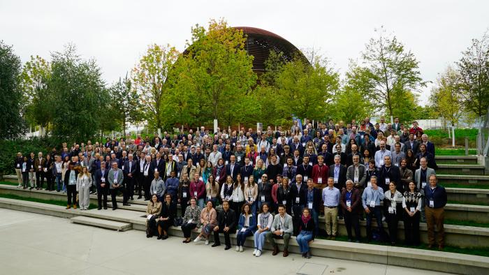 group photo of a lot of people in front of globe-shaped building and some trees